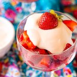 Close up photo of Strawberries Romanoff in a glass stemmed dish on a blue napkin.