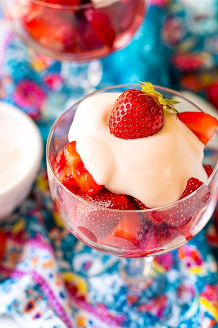 Close up photo of Strawberries Romanoff in a glass stemmed dish on a blue napkin.