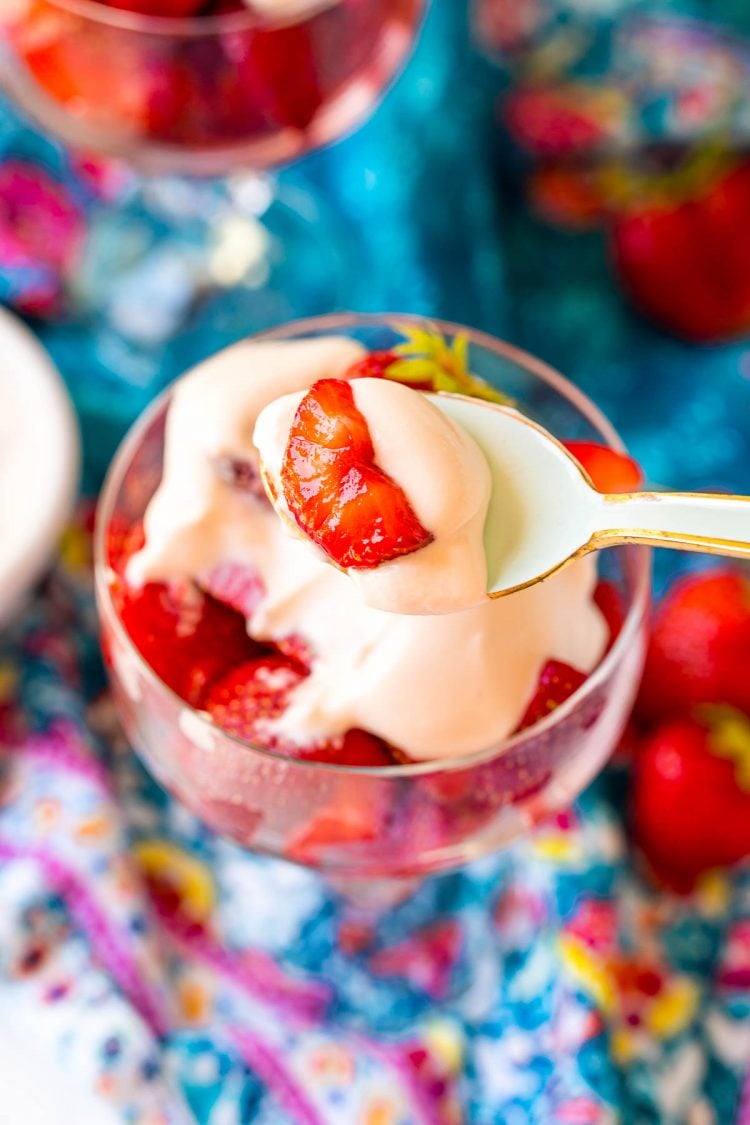 A spoon with a bite of Strawberries Romanoff being held to the camera.