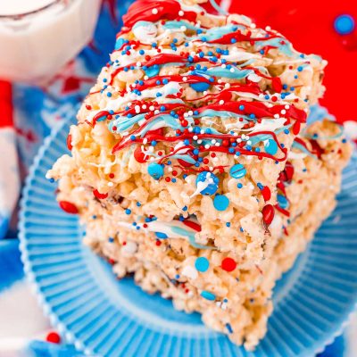 Close up photo of a stack of three rice krispie treats with red, white, and blue candy drizzle and sprinkles.