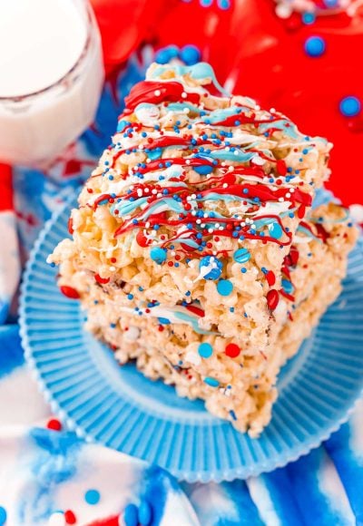 Close up photo of a stack of three rice krispie treats with red, white, and blue candy drizzle and sprinkles.