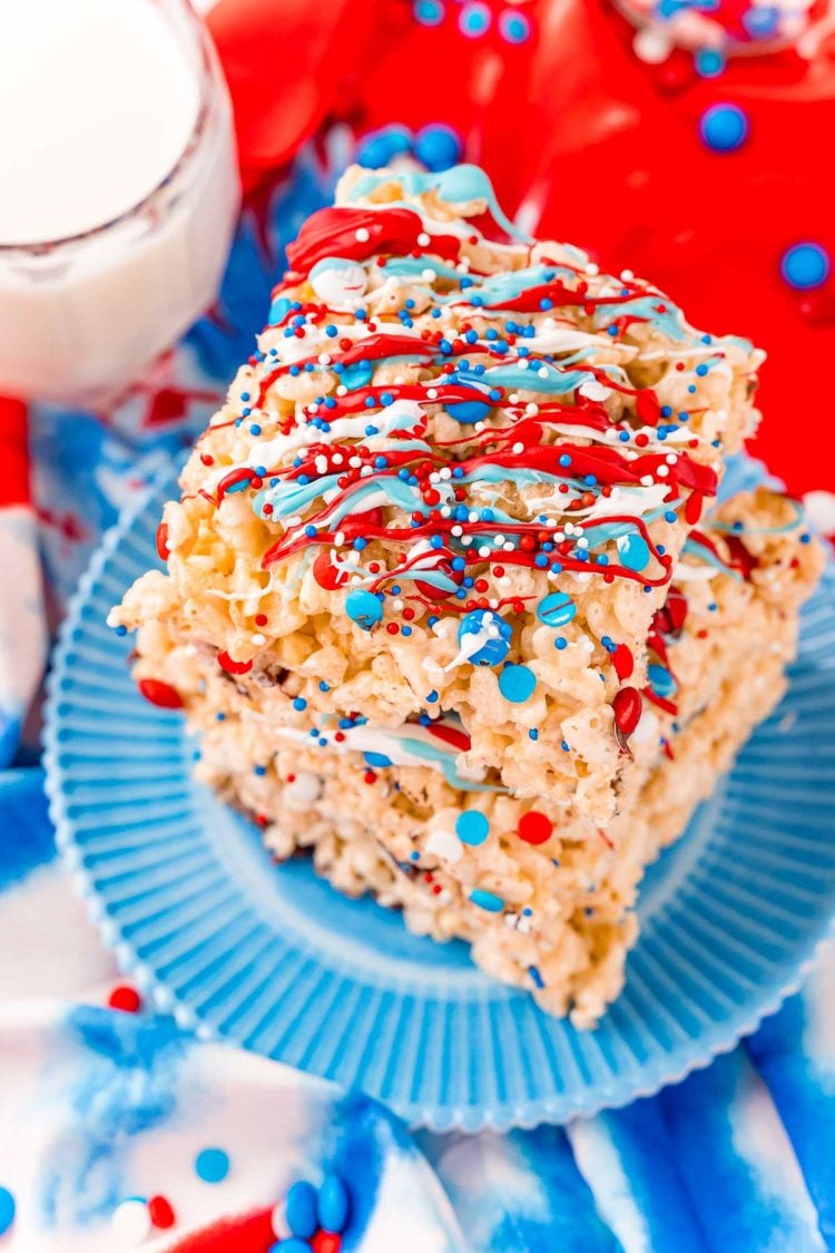 Close up photo of a stack of three rice krispie treats with red, white, and blue candy drizzle and sprinkles.