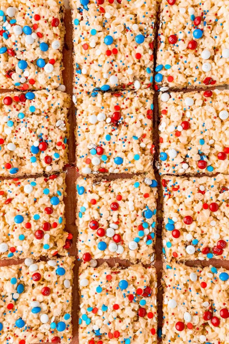 Overehad photo of red, white, and blue rice krispie treats on a cutting board chopped into squares.