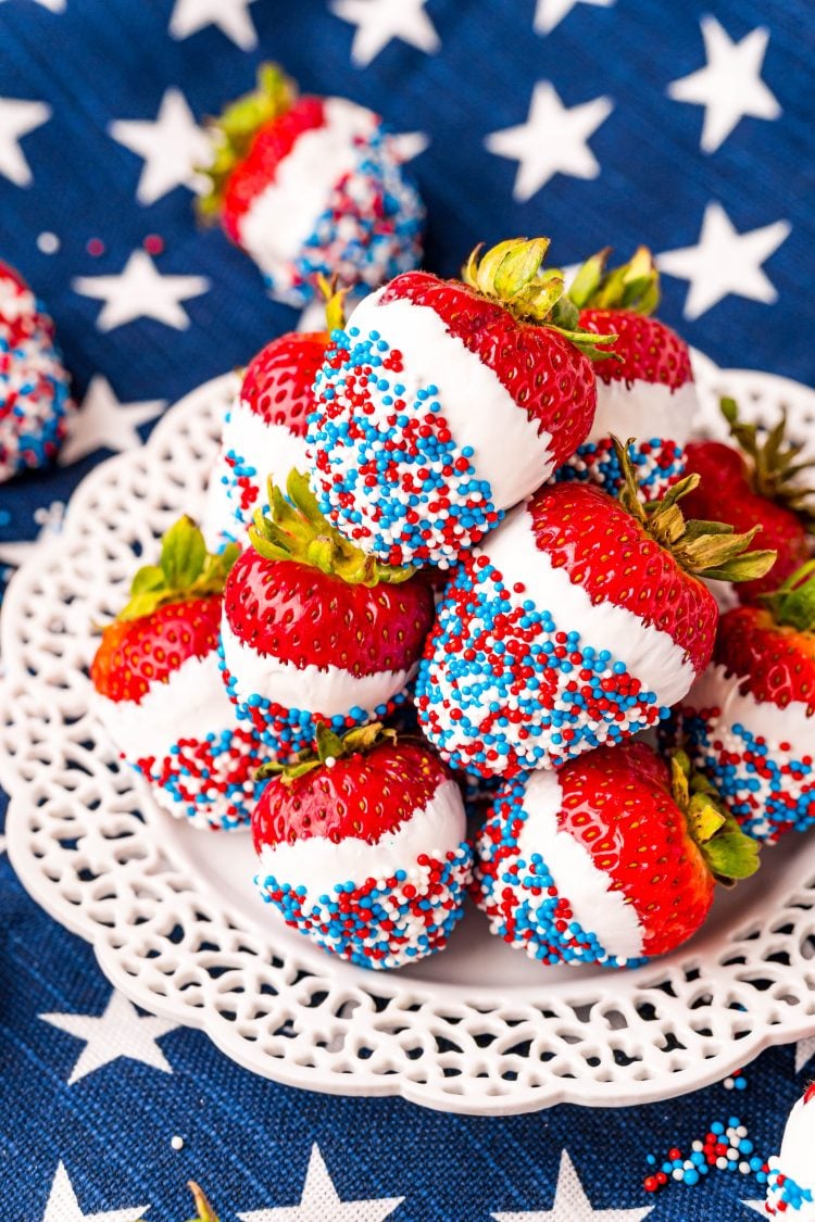 Close up photo of a while plate on a blue and what star napkin with strawberries that have been dipped in white candy then in red, white, and blue sprinkles.