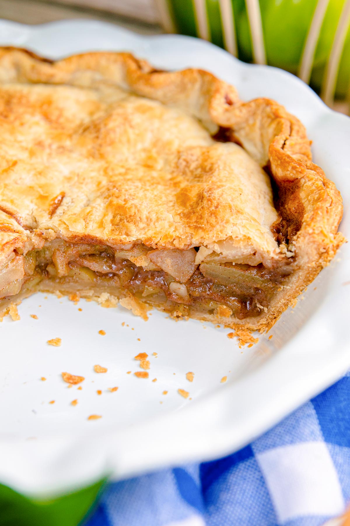 Apple pie in a white pie dish with some pieces missing.