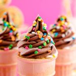 Close up photo of cupcakes in ice cream cones topped with a vanilla and chocolate frosting.