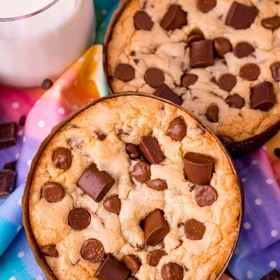 Disney num num cookies on a rainbow napkin with a glass of milk next to them.