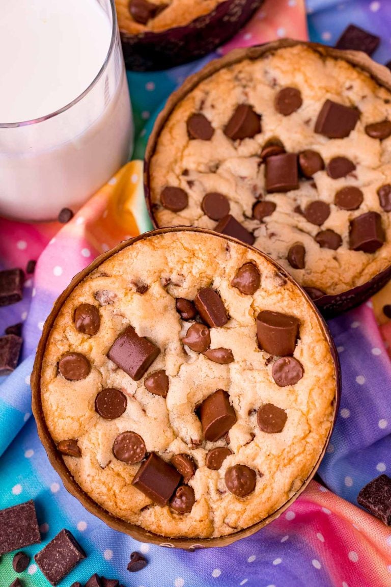 Disney num num cookies on a rainbow napkin with a glass of milk next to them.