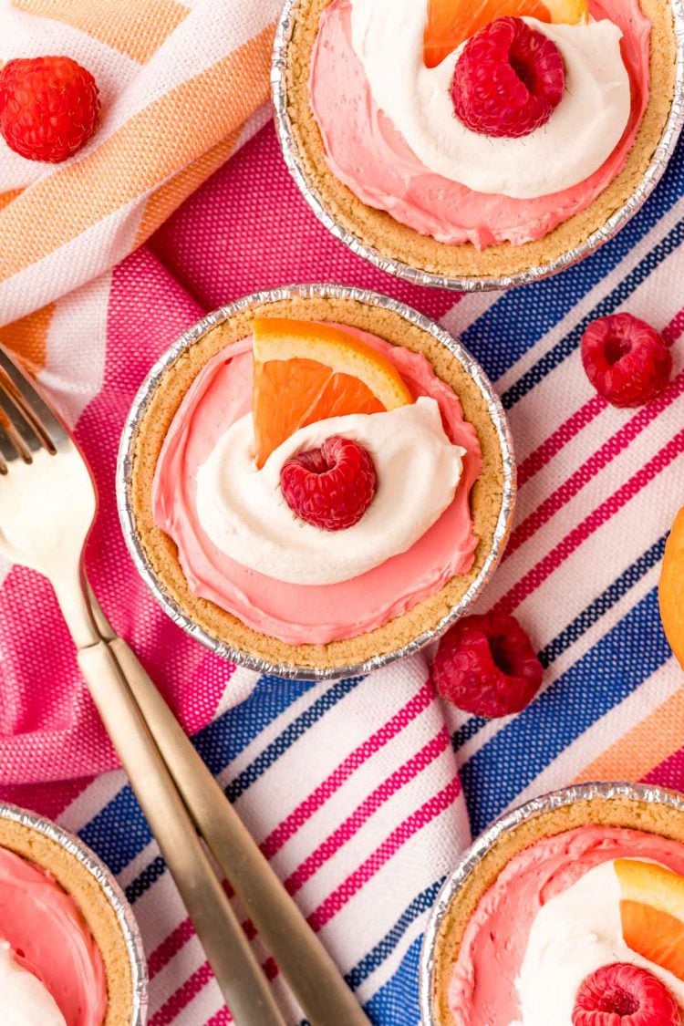 Overhead photo of mini kool aid pies on a blue, pink, and white striped napkin.