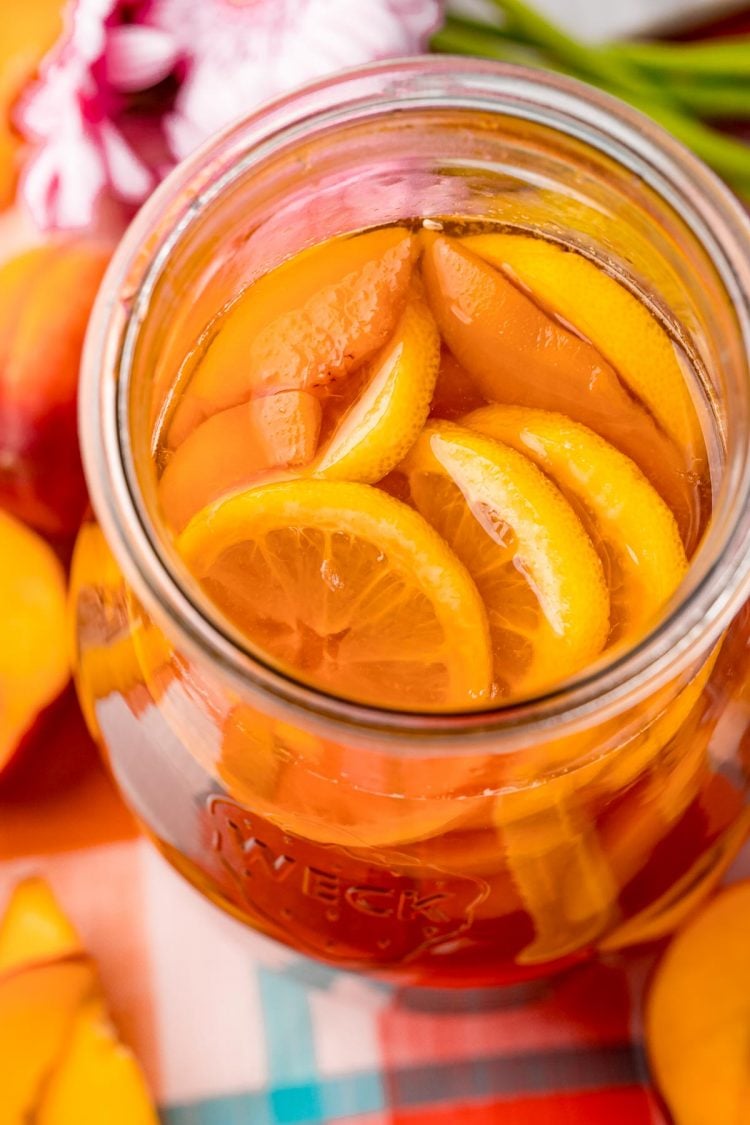 A large pitcher of peach iced tea on a plaid napkin.