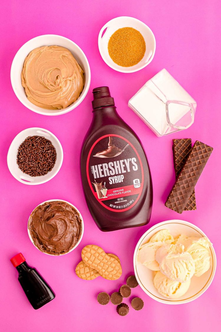 Overhead photo of ingredients to make peanut butter milkshake (freak shake) on a pink surface.