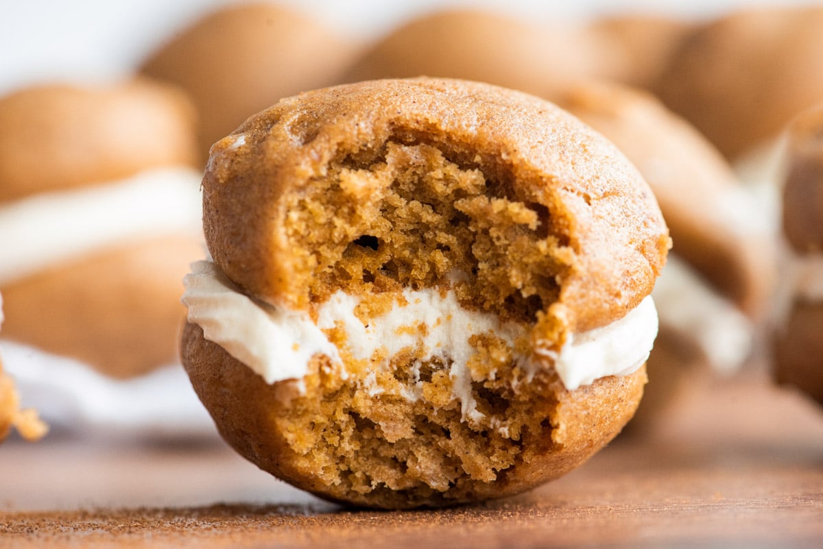 Close up photo of a pumpkin whoopie pie with a bite taken out if it.