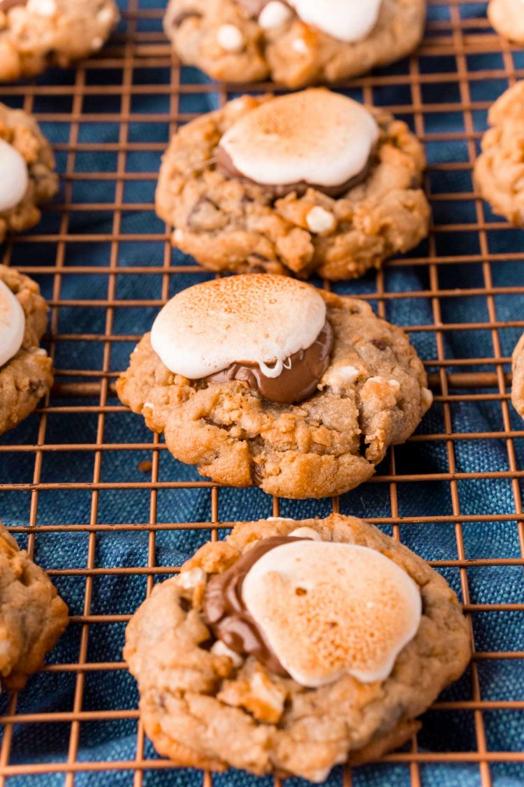 Close up photo of rows of s'mores cookies on a wire rack on a blue napkin.