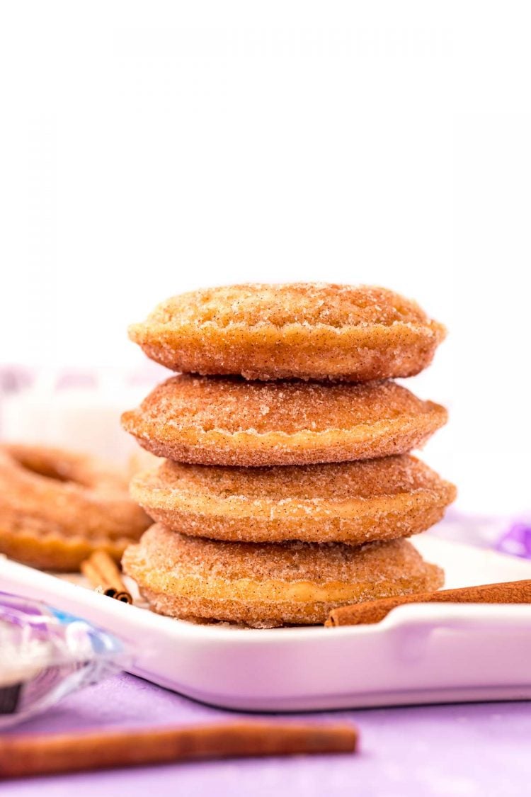 4 uncrustables donuts stacked on top of each other on a white serving tray on a purple surface.