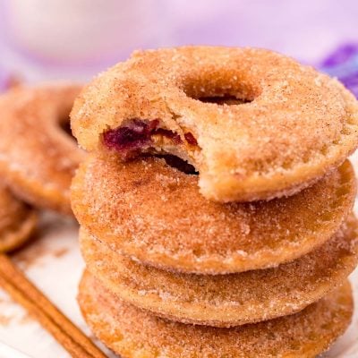Close up photo of a stack of Uncrustables donuts on a white tray with the top one missing a bite.