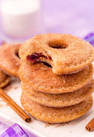 Close up photo of a stack of Uncrustables donuts on a white tray with the top one missing a bite.