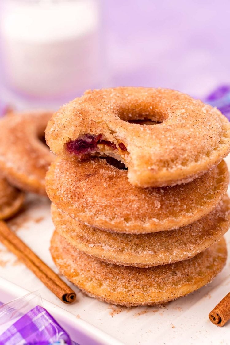 Close up photo of a stack of Uncrustables donuts on a white tray with the top one missing a bite.