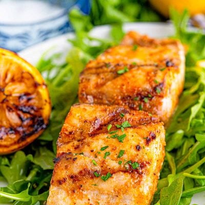 Close up photo of grilled mahi mahi on a bed of greens.