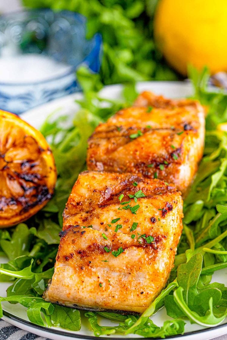 Close up photo of grilled mahi mahi on a bed of greens.