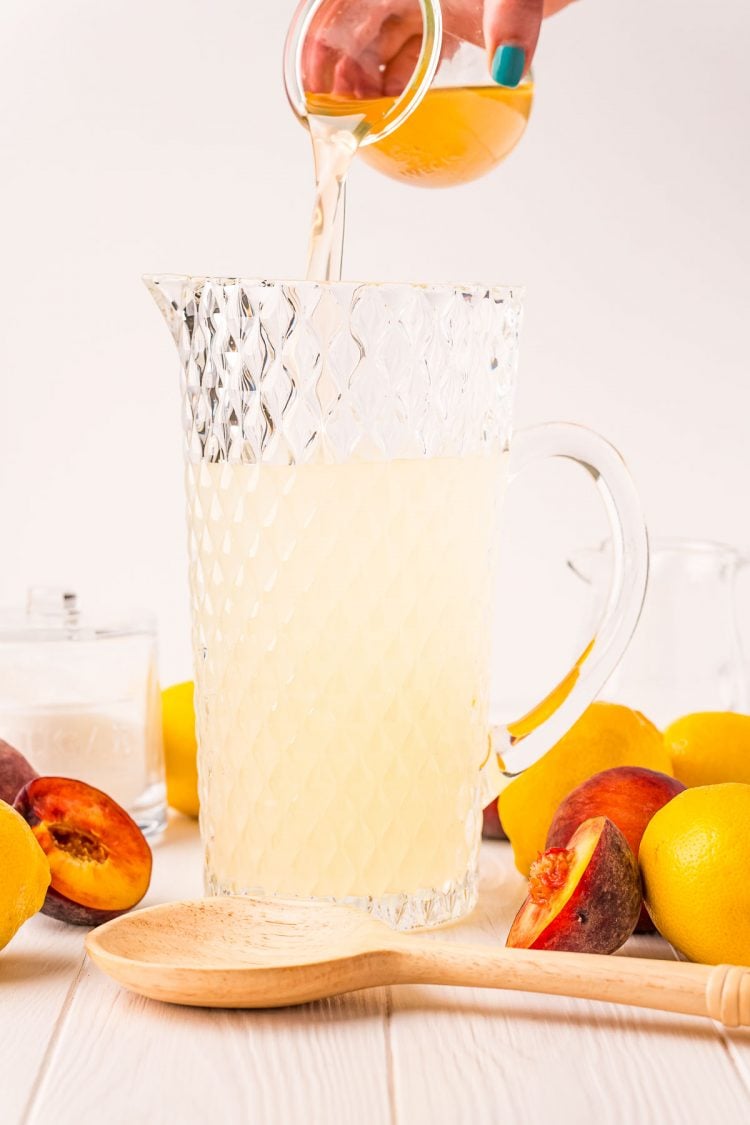 Photo of peach simple syrup being poured into a large pitcher to make lemonade.