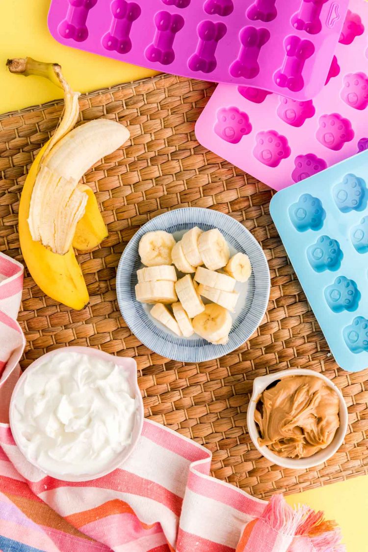 Overhead photo of ingredients to make frozen dog treats on a wicker board.