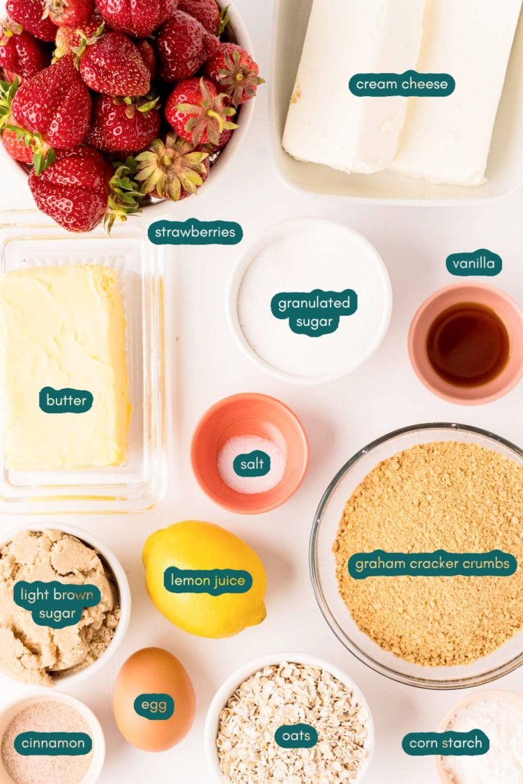 Ingredients to make strawberry cheesecake bars prepped on a white table.