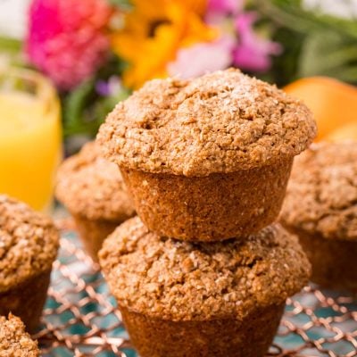 Two bran muffins stacked on top of each other on a wire rack.