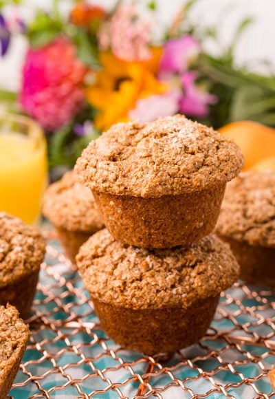 Two bran muffins stacked on top of each other on a wire rack.