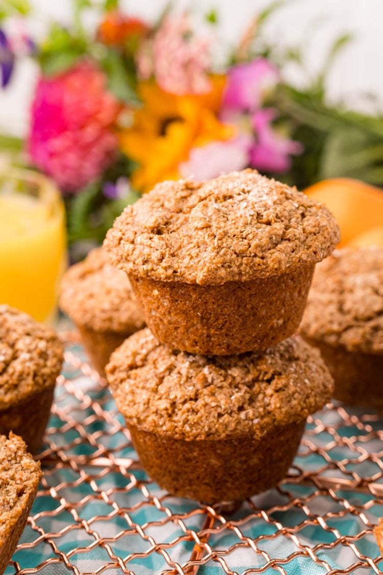 Two bran muffins stacked on top of each other on a wire rack.