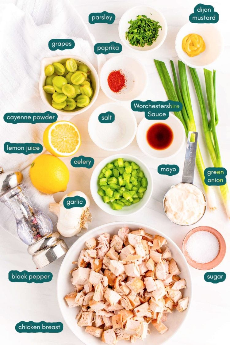 Ingredients to make chicken salad with grapes are prepped on a white countertop.