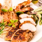 Close up photo of a white platter with a broken down grilled chicken on it.