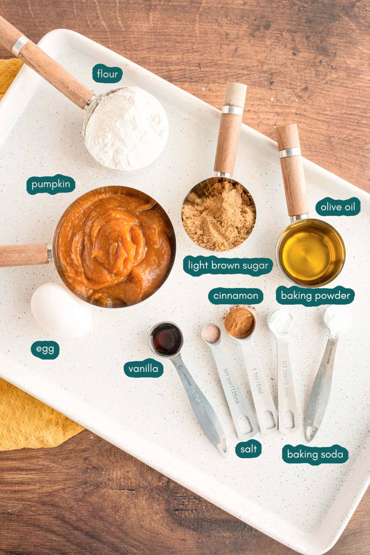 Overhead photo of ingredients to make pumpkin whoopie pies prepared on a white plate on a wooden table.