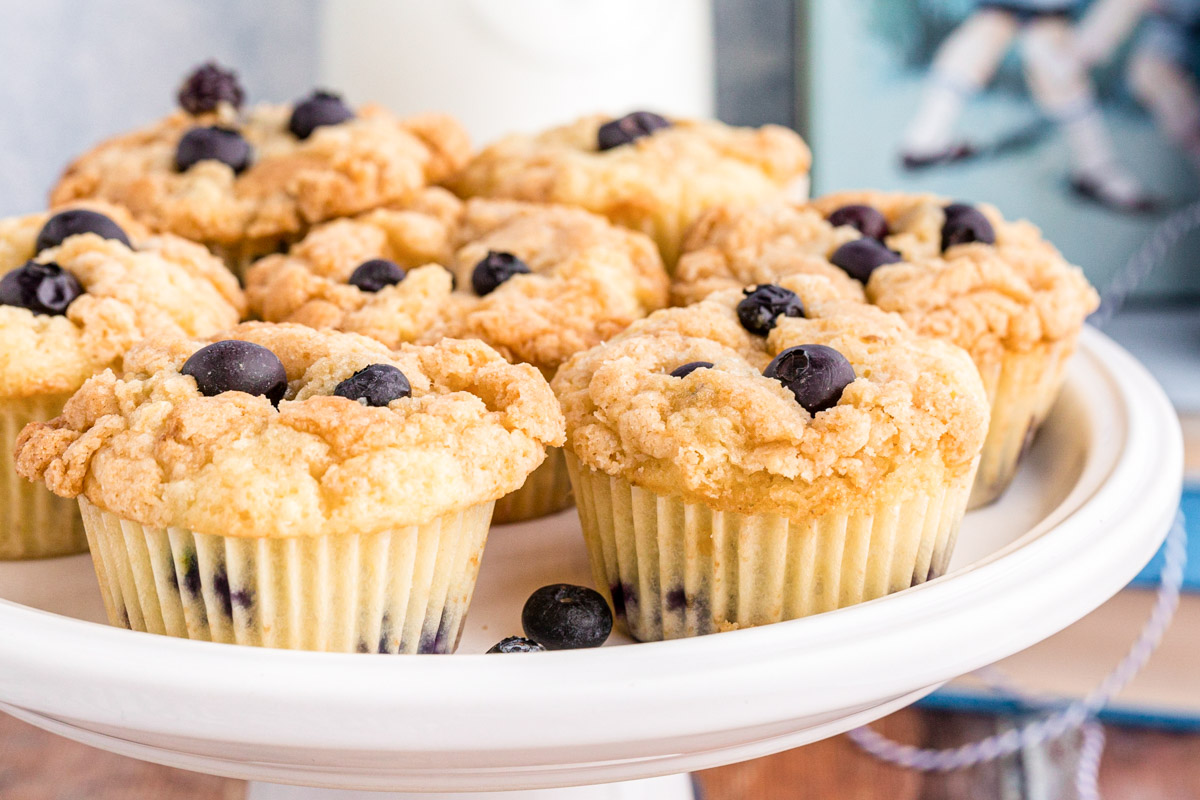 Sourdough blueberry muffins on a white cake stand.