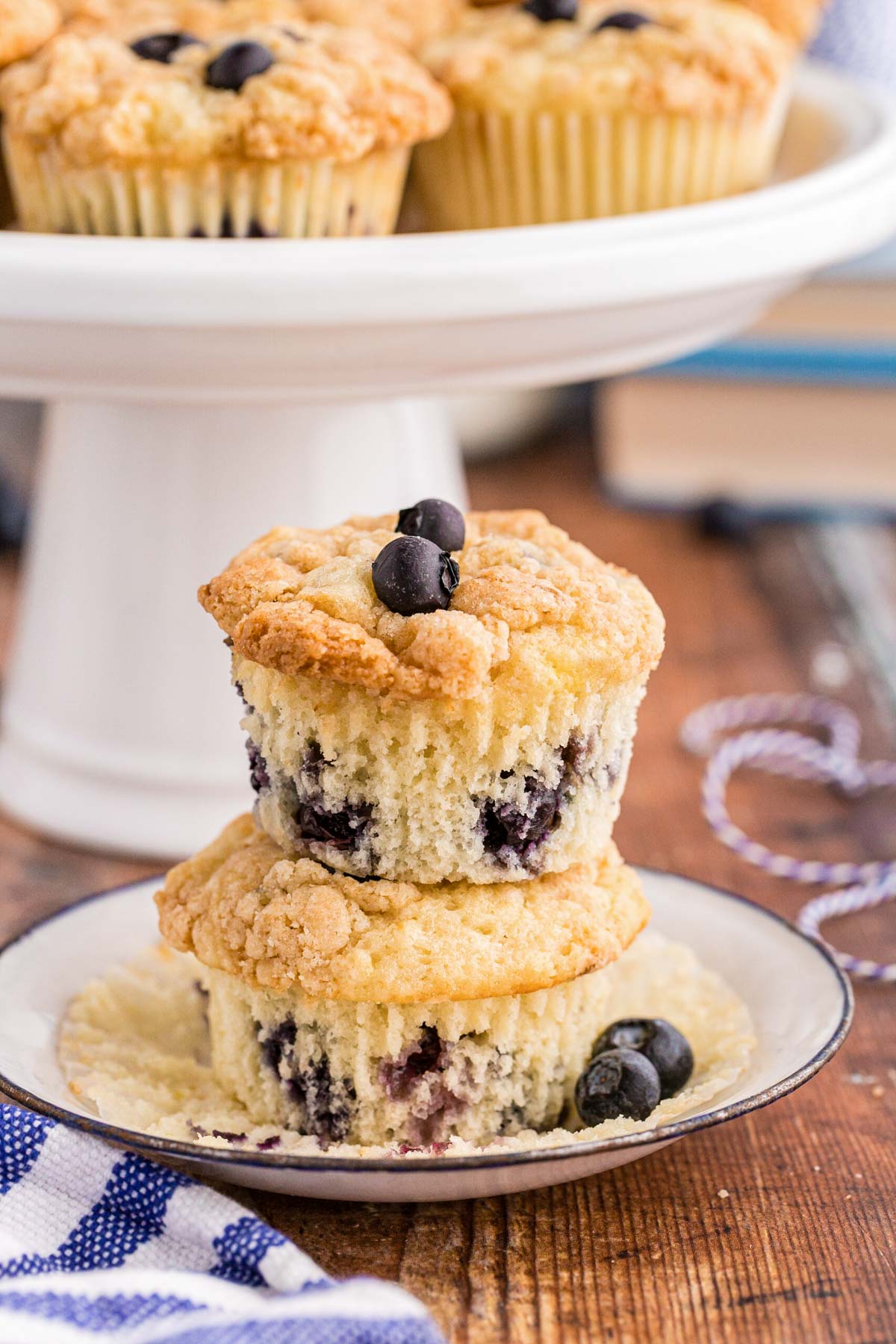 Two blueberry muffins made with sourdough discard stacked on a small white plate.