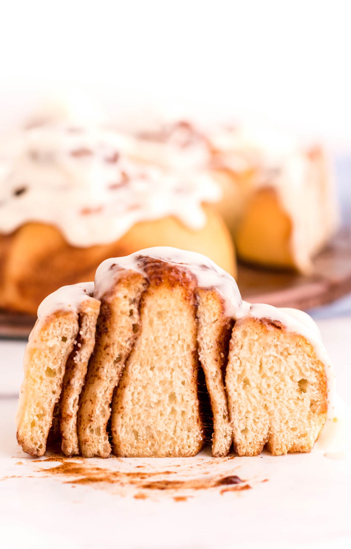 Sourdough cinnamon rolls on a white surface sliced in half to show the layers.