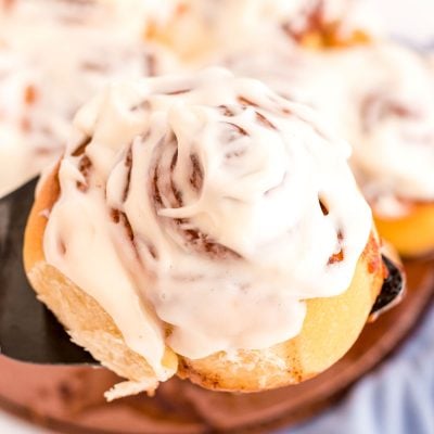 Sourdough Cinnamon Rolls being lifted out of the pan with a spatula.