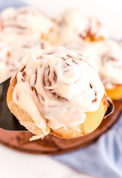 Sourdough Cinnamon Rolls being lifted out of the pan with a spatula.