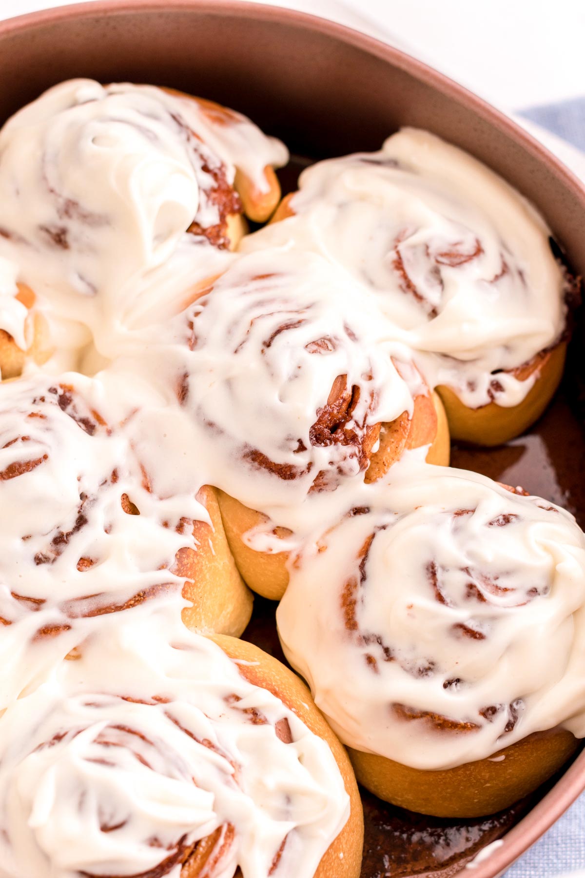 Close up photo of sourdough cinnamon rolls in a round baking pan.