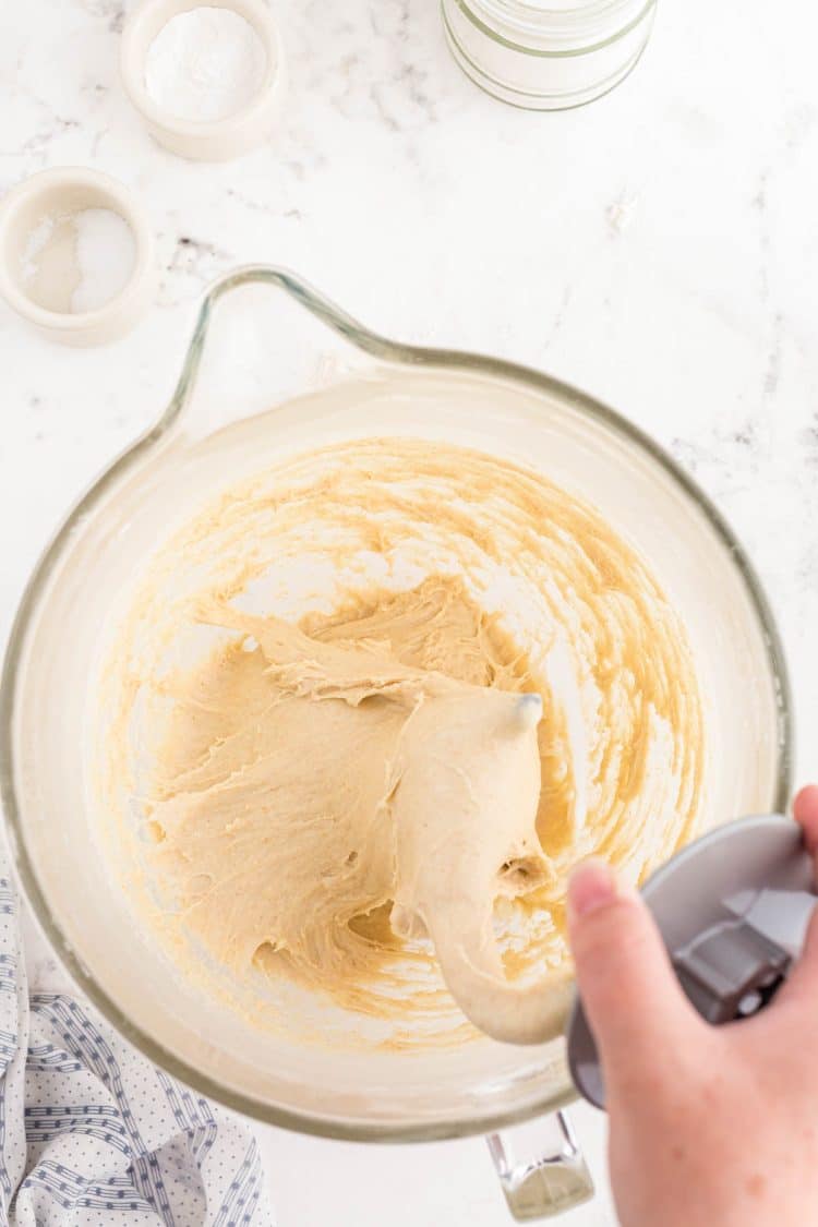 A dough hook in a mixing bowl making dinner rolls.