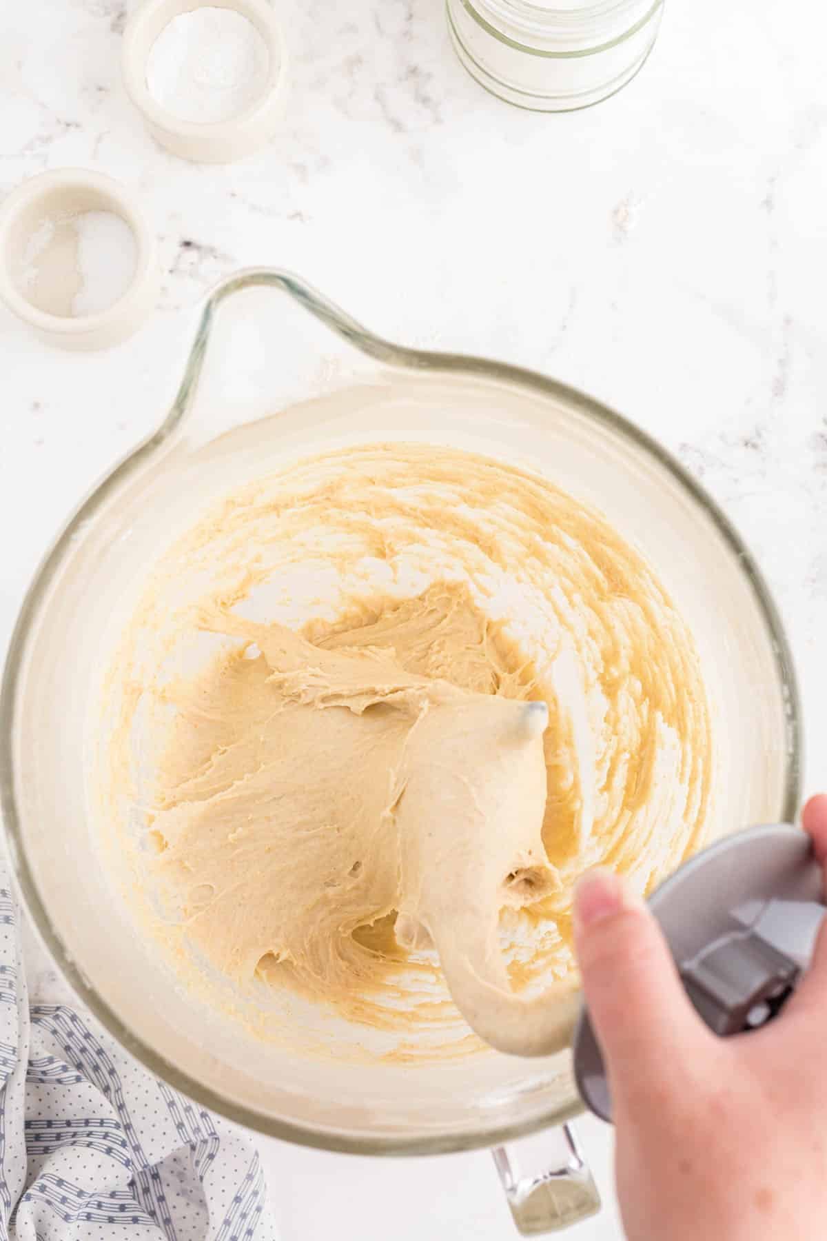 A dough hook in a mixing bowl making dinner rolls.
