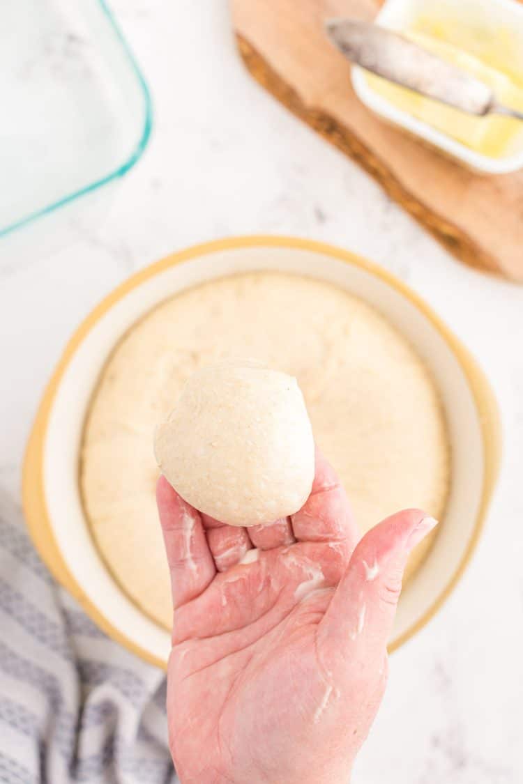 A woman's hand holding a ball of dough.