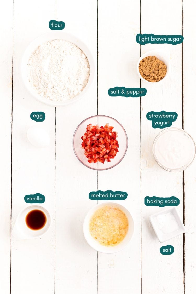 Overhead photo of ingredients to make strawberry donuts on a white wooden table.