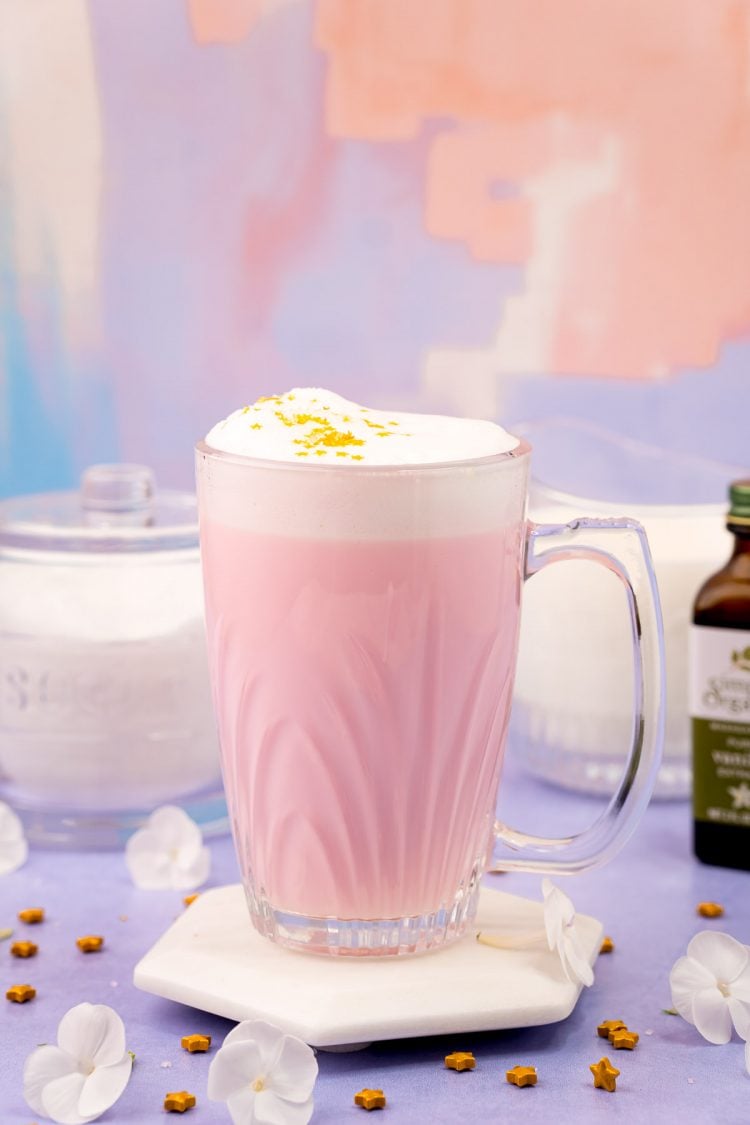 A mug of pink Angel milk on a purple surface.