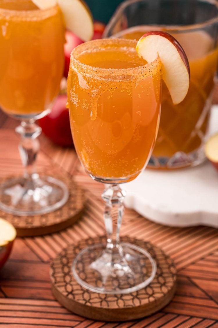 Close up photo of an apple cider mimosa in a glass garnished with an apple slice.