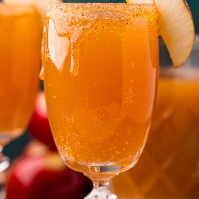 Close up photo of an apple cider mimosa in a glass garnished with an apple slice.