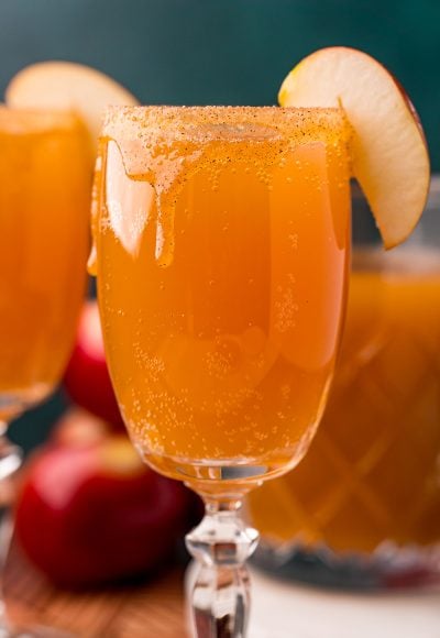 Close up photo of an apple cider mimosa in a glass garnished with an apple slice.