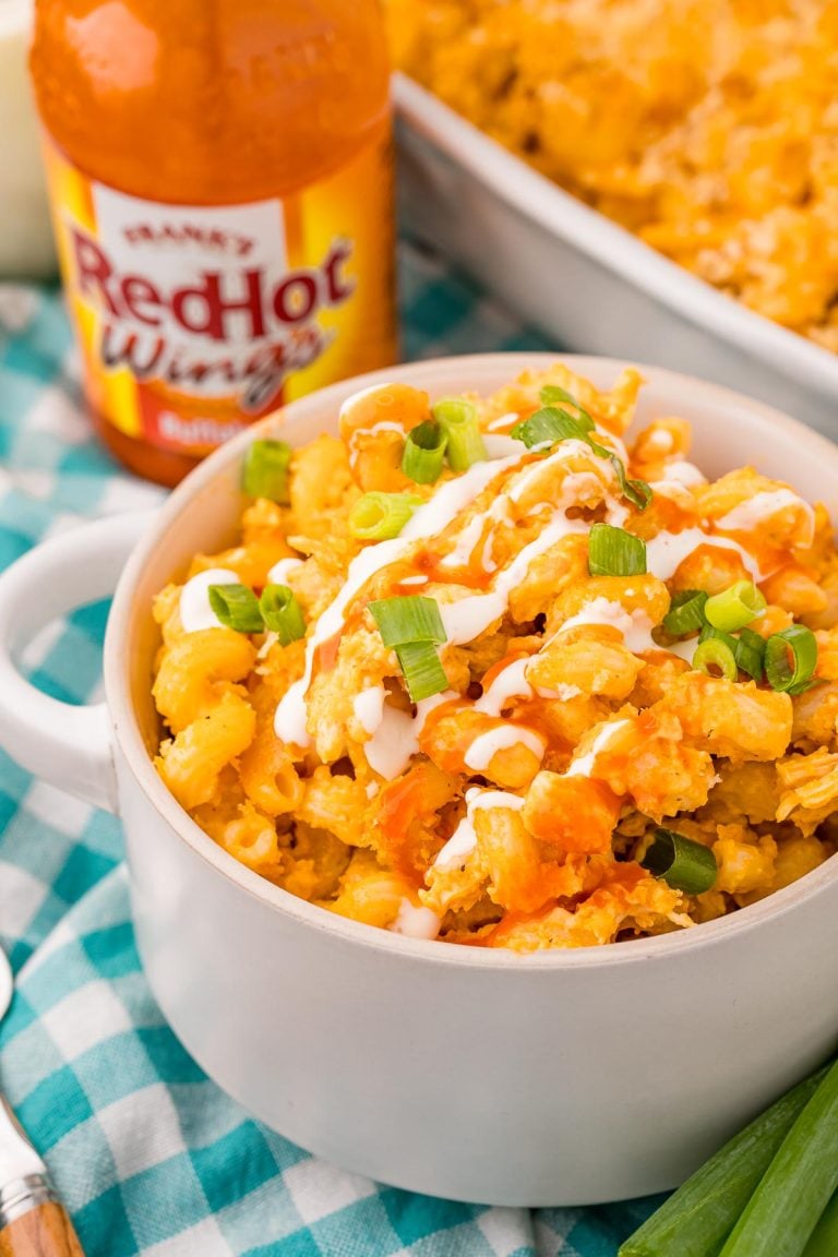 Close up photo of a bowl of buffalo chicken mac and cheese on a teal and white gingham napkin.