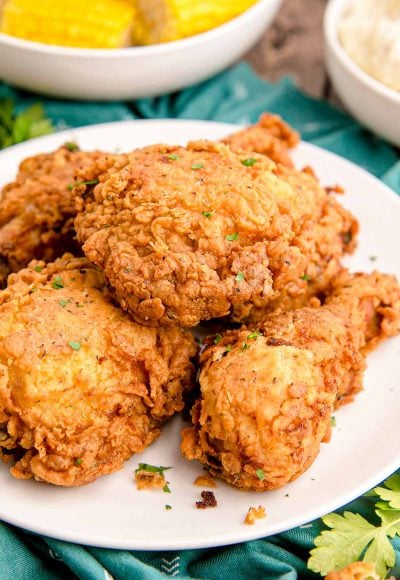 Close up photo of buttermilk fried chicken on a white plate on a teal napkin.