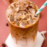 Close up photo of a glass filled with an iced caramel macchiato.