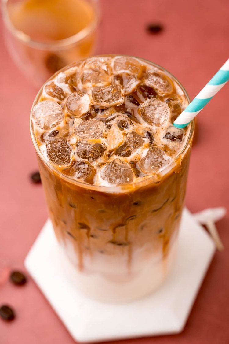 Close up photo of a glass filled with an iced caramel macchiato.